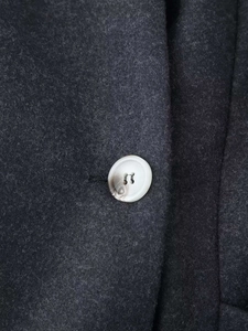 Macro detail of the gray wool blend coat fabric with a premium marble texture button