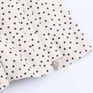 Detailed close-up of cream polka dot midi dress showing premium fabric texture and hemline