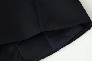 Close-up detail of smooth hem stitching and satin luster fabric on black jacket