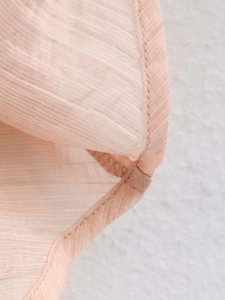 Vue détaillée de la texture du tissu abricot clair et des coutures du chemisier pour femme