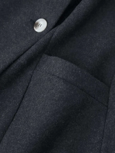 Detailed macro view of charcoal grey wool fabric with marble texture button and pocket seam