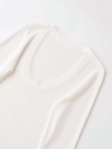 Detailed view of white knit top showing deep U-neckline and smooth shoulder seams