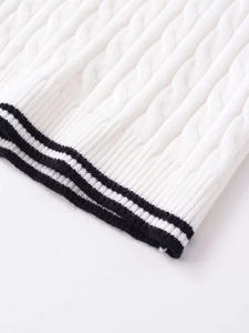 Close-up of white cable knit fabric with black striped ribbed hem detail