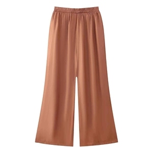 Detail of burnt orange tencel wide-leg pants with elastic waist and satin texture