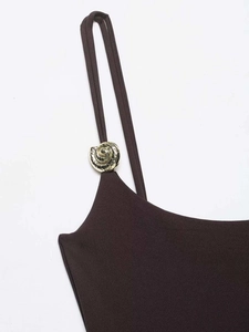 Detail of dark brown bodysuit with slim straps and golden metallic shell buckles