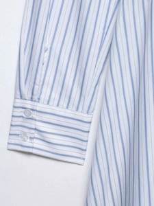 Detail of blue and white striped shirt cuff featuring two clear buttons and neat stitching