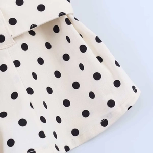 Detailed macro view of vintage black polka dots on ivory fabric with fine stitching