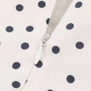 Close-up of a white polka dot dress featuring a high-quality concealed back zipper detail
