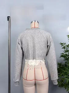 Detailed close-up of grey sweatshirt with delicate white lace hem on fashion mannequin