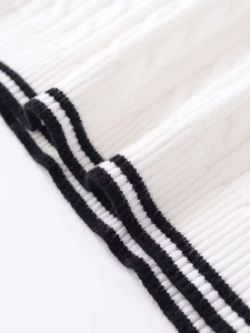 Detail of white cable knit texture with black striped ribbed hem on a short sleeve sweater