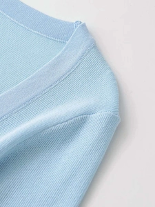 Detail of light blue knit top featuring a ribbed round neckline and soft fabric texture