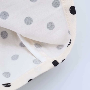 Close-up detail of white fabric with black polka dots and high-quality hemmed stitching