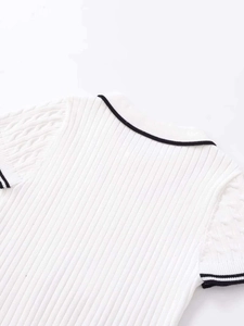 Detail of white cable knit short sleeve sweater with black contrast trim neckline