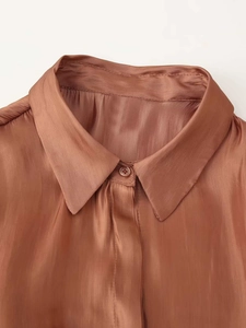 Detail of copper satin shirt collar with smooth silk finish and shoulder pleats