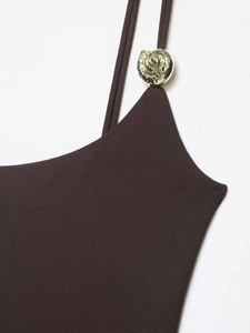 Detail of dark coffee bodysuit featuring fine shoulder straps and a gold spiral metal buckle