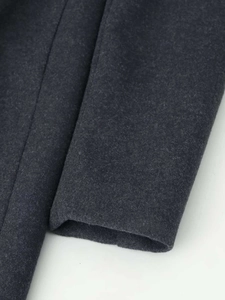 Detailed macro view of dark grey wool coat sleeve with high-quality stitching and texture
