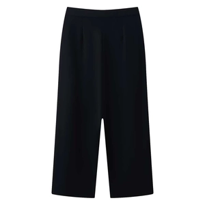 Close-up of high-waist black trousers with pleated details and straight-leg tailoring