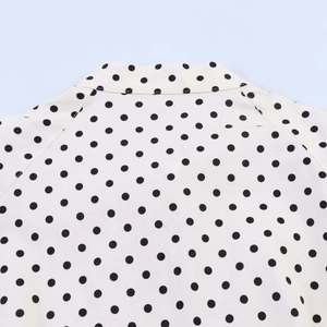 Detailed close-up of retro white blouse with black polka dots and stand collar tie