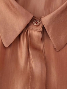 Detailed close-up of a satin silk shirt collar with a classic button and vertical texture