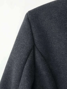 Macro shot of dark grey wool blend fabric showing fine texture and premium stitching detail