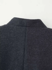 Close-up detail of dark grey wool blend fabric texture and fine stitching on the coat