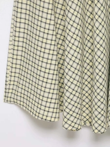 Detail von gelb-schwarzem Plaid-Seersucker-Stoff mit Webstruktur an einem Midikleid