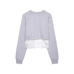 Detailed view of grey sweatshirt featuring white lace patchwork hem and raglan sleeves