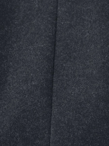 Detailed macro view of charcoal grey wool fabric texture and stitching on winter coat