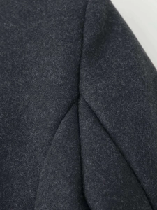 Detailed macro view of pleated shoulder design on a dark grey wool blend coat