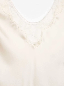 Gros plan d'un débardeur en satin crème avec bordure en dentelle et décolleté en V élégant