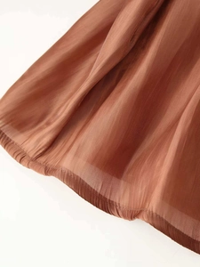 Detail shot of brown pleated tencel fabric showing sheer texture and vertical stripes