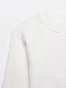 Detailed view of white sweatshirt featuring premium ribbed neckline and raglan sleeves
