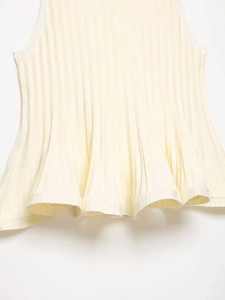 Détail de la maille côtelée et de l'élégant ourlet à volants sur un haut crème