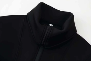 Detailed close-up of a black zip-up collar with a size S label and knit texture