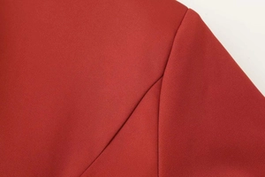 Macro detail of deep red twill fabric and high-quality shoulder stitching on a long-sleeve suit