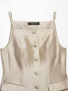 Detail of champagne satin top featuring a square neckline, covered buttons, and thin straps