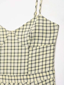 Detail eines gelb-schwarzen Gingham-Hemdchens mit dünnen Trägern und strukturierter Brust