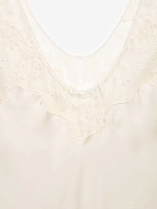 Détail d'un caraco élégant en satin crème avec bordure en dentelle au décolleté