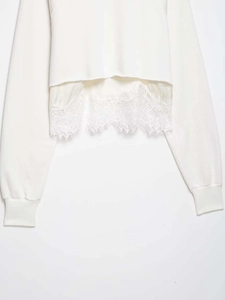 Detail of white cropped sweatshirt featuring intricate lace trim hem and ribbed cuffs