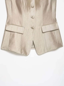 Detail of champagne satin vest with three fabric buttons and flap pockets
