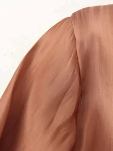 Detail view of terracotta satin shirt shoulder seams and twill textured fabric