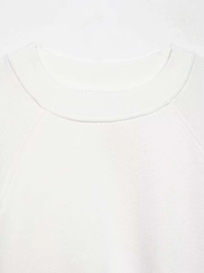 Detail shot of white ribbed knit sweatshirt with delicate lace splicing and stitching