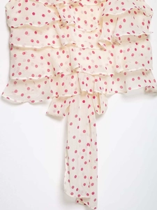Close-up of pink polka dots on off-white chiffon fabric with tiered ruffles and long ribbons