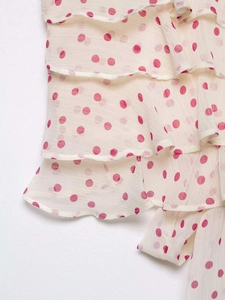 Detail of multi-layer ruffles on off-white sleeveless top with pink polka dot pattern