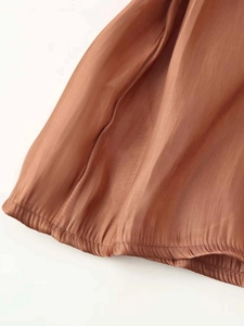 Detailed close-up of brown satin fabric showing smooth texture and elastic hem design
