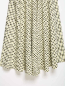 Detail des gelb karierten Midikleid-Saums mit strukturierter Textur und Faltenwurf