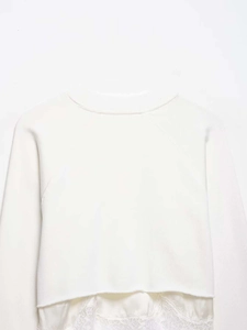 Detail of white sweatshirt featuring lace patchwork hem and layered satin stitching