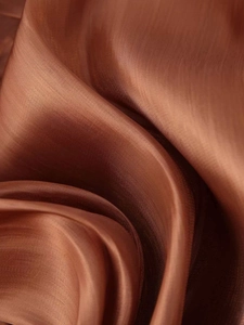 Macro shot of copper brown silk-like fabric with glossy metallic texture and elegant drapes