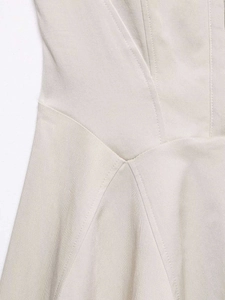 Detailed close-up showing beige twill fabric texture and geometric seam stitching on dress