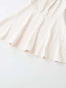 Detailed close-up of flowing A-line hemline on a white summer halter neck dress
